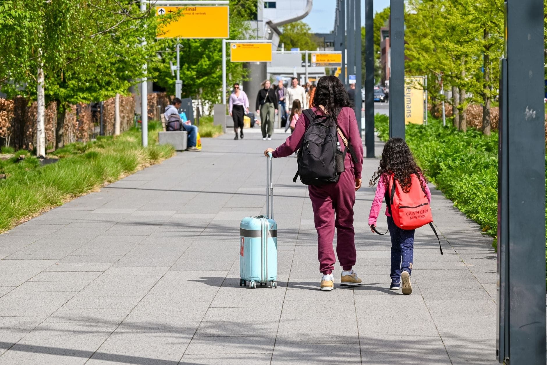 A family walking out of an airport terminal with suitcases, ready for a pre-booked maxi cab transfer to their Perth suburb