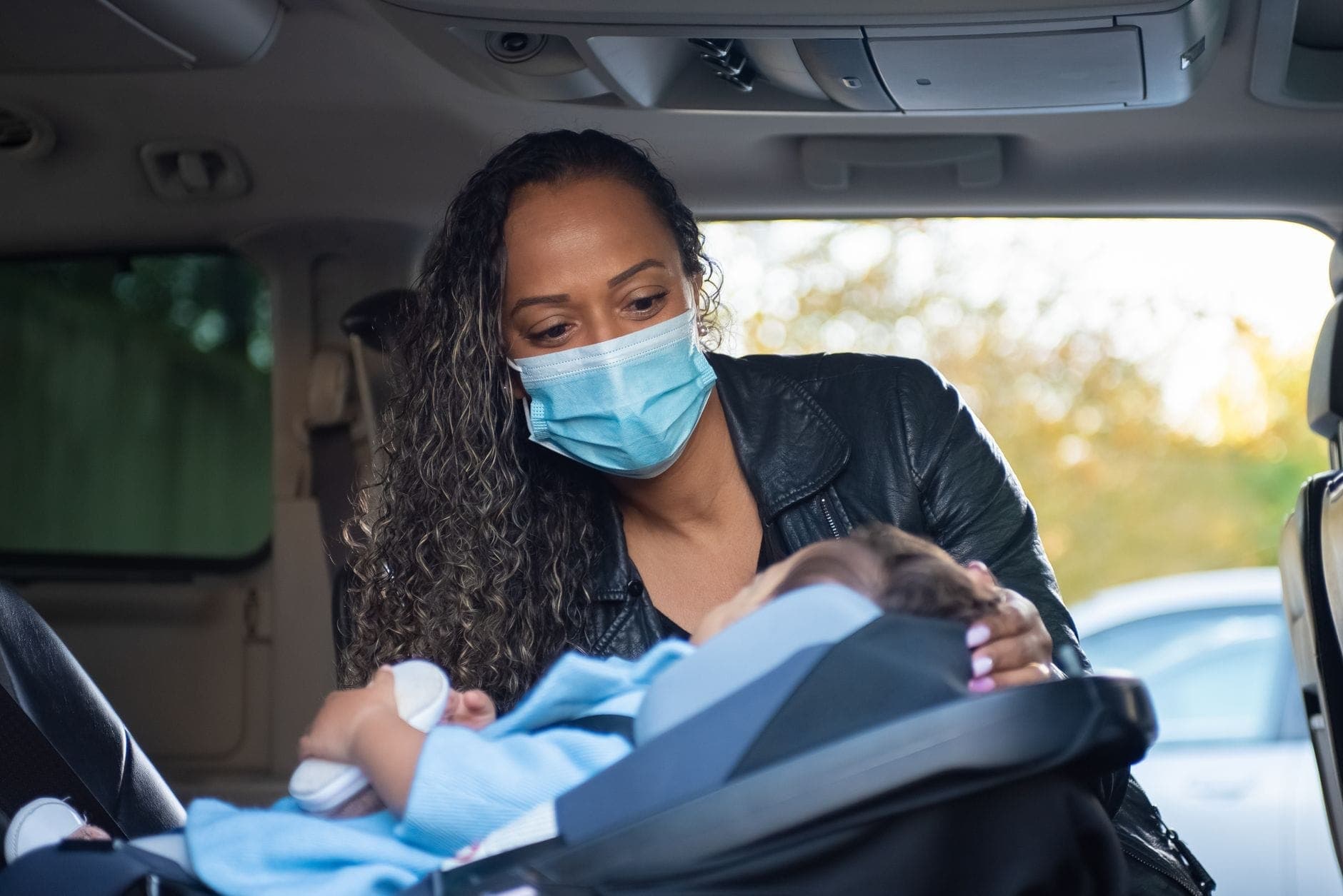 A parent buckling a child into a car seat, matching the compliant baby seats, capsules and boosters fitted in Perth maxi cabs